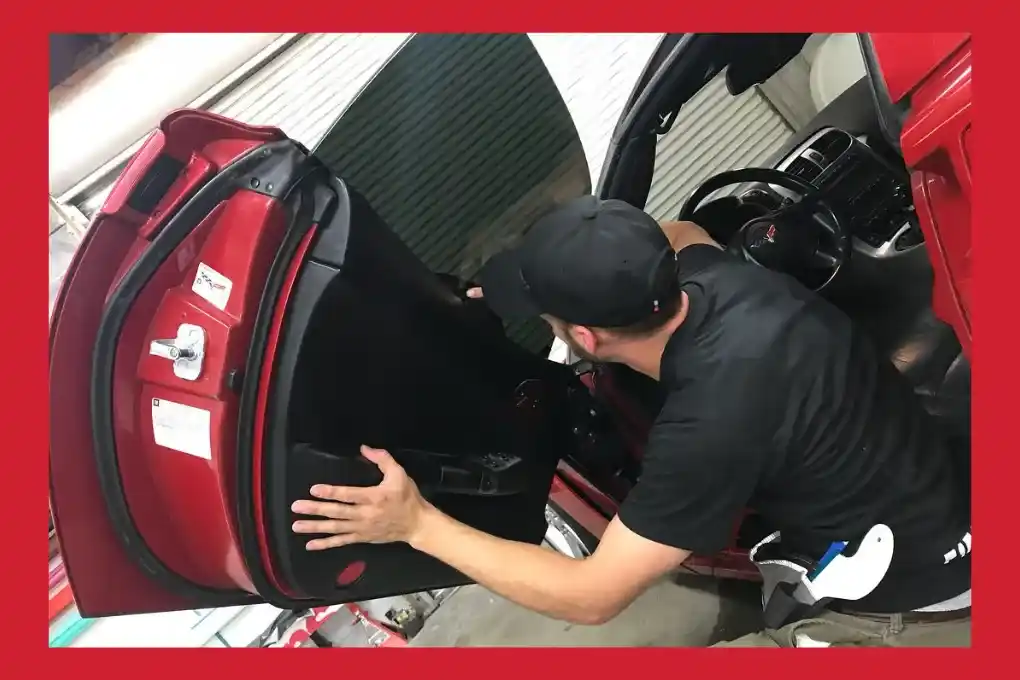 A man is opening the door of a red car, preparing to enter the vehicle.