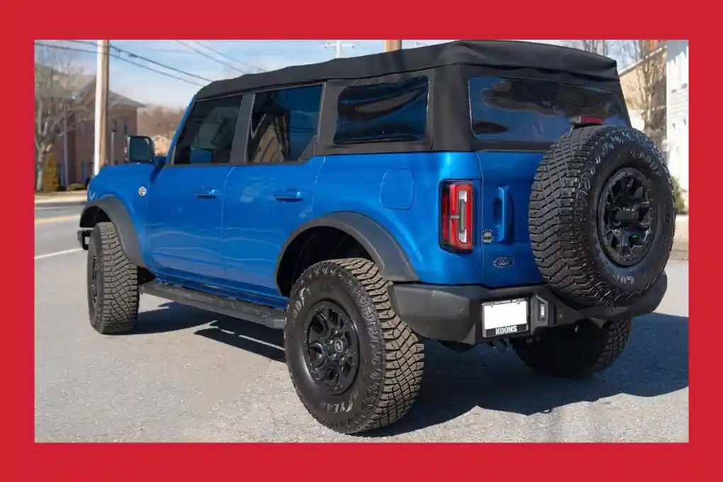 The rear view of a blue Ford Bronco, showcasing its distinctive design and rugged features.