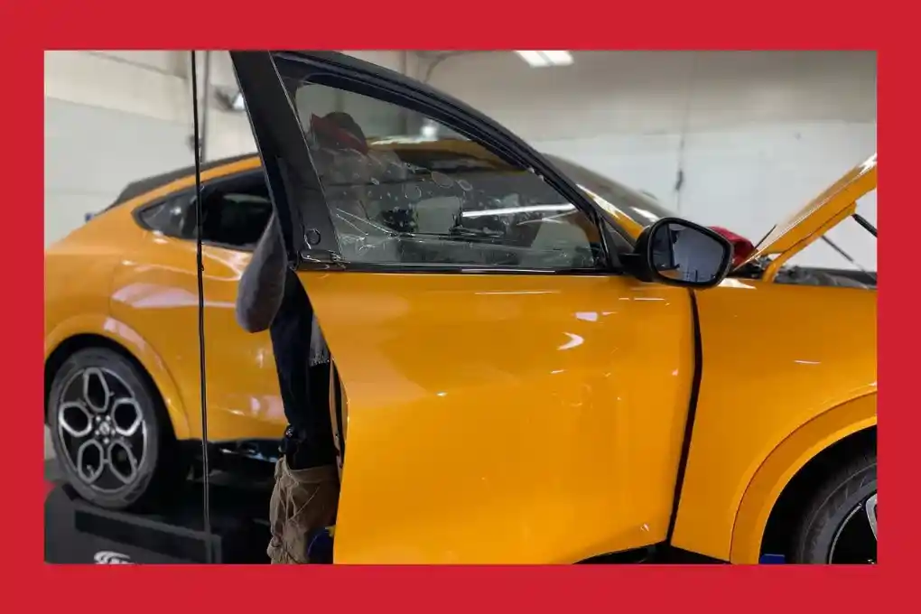 A man is focused on fixing a car in a spacious garage, with various tools and parts visible around him.