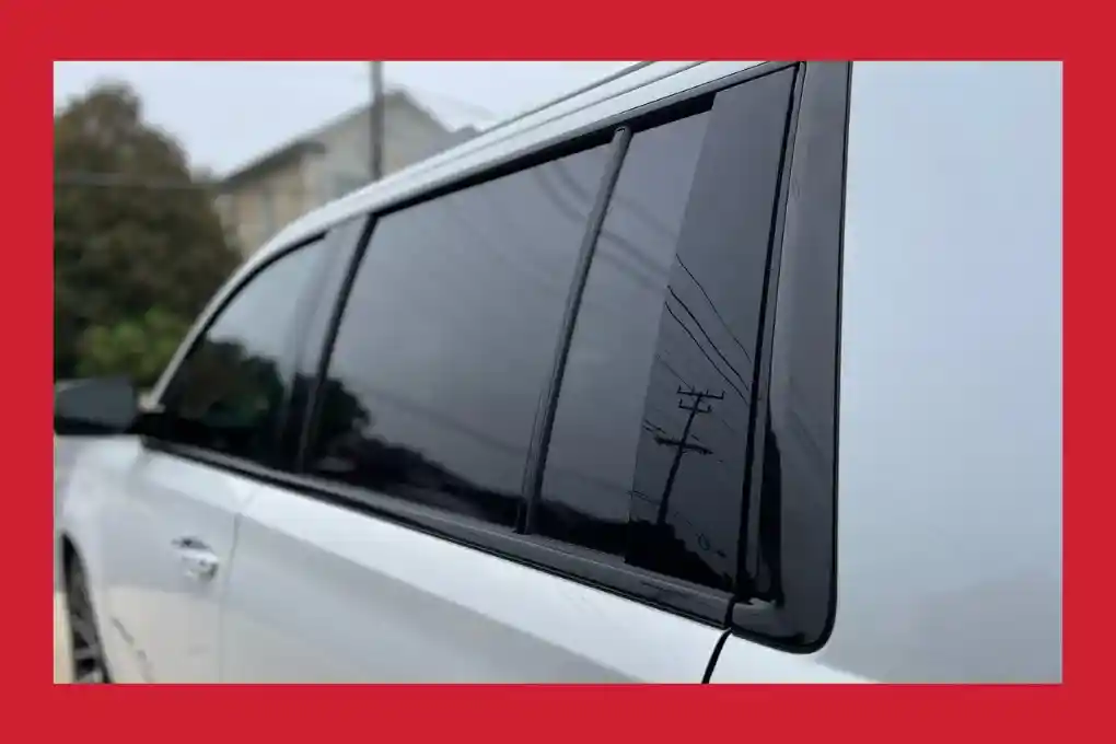 Close-up of a white car's side window with the inscription "the best" visible.